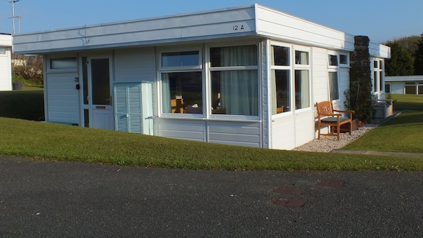 A small, single-story building with a flat roof, large windows, and a door. -  Chalet Cwtch, a cosy 5 bed holiday cottage in Roch, Pembrokeshire (Roch)