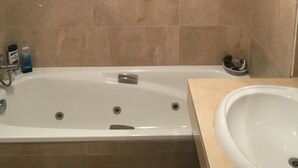 Un baño con bañera, lavamanos y artículos de aseo sobre el mostrador.