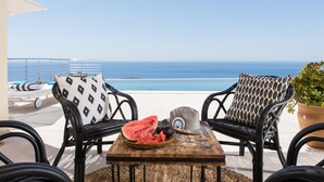 A terrace with wicker chairs, a table with a bowl of watermelon and olives, and a view of the sea. - THETIS, south coast with amazing views and infinity pool! (Chania)