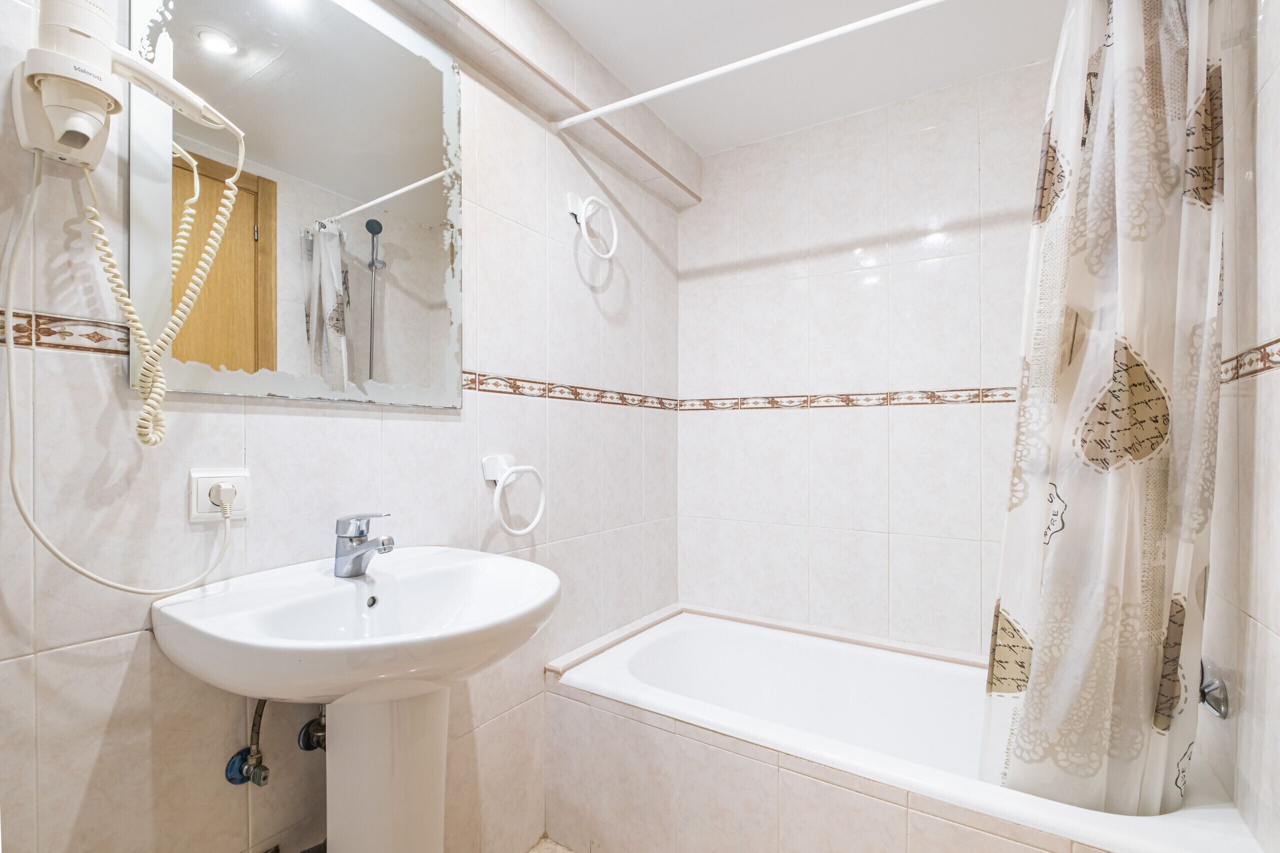 A bathroom with a sink, mirror, and shower.