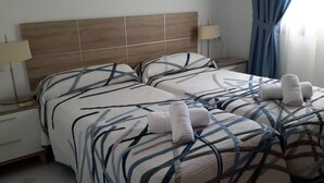 A double room with a wooden headboard, two beds with patterned bedding, bedside lamps, and a window with curtains. - Inviting, bright 2-Bedroom El Rancho villa in prestigious La Manga Club Resort (La Manga Club)
