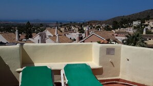 A rooftop terrace with two green lounge chairs, a view of a coastal town, and a clear sky. - Inviting, bright 2-Bedroom El Rancho villa in prestigious La Manga Club Resort (La Manga Club)