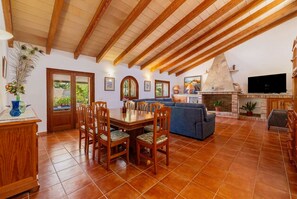 Ein großzügiger Wohnbereich mit Esstisch, Stühlen, einer Couch und einem Kamin.