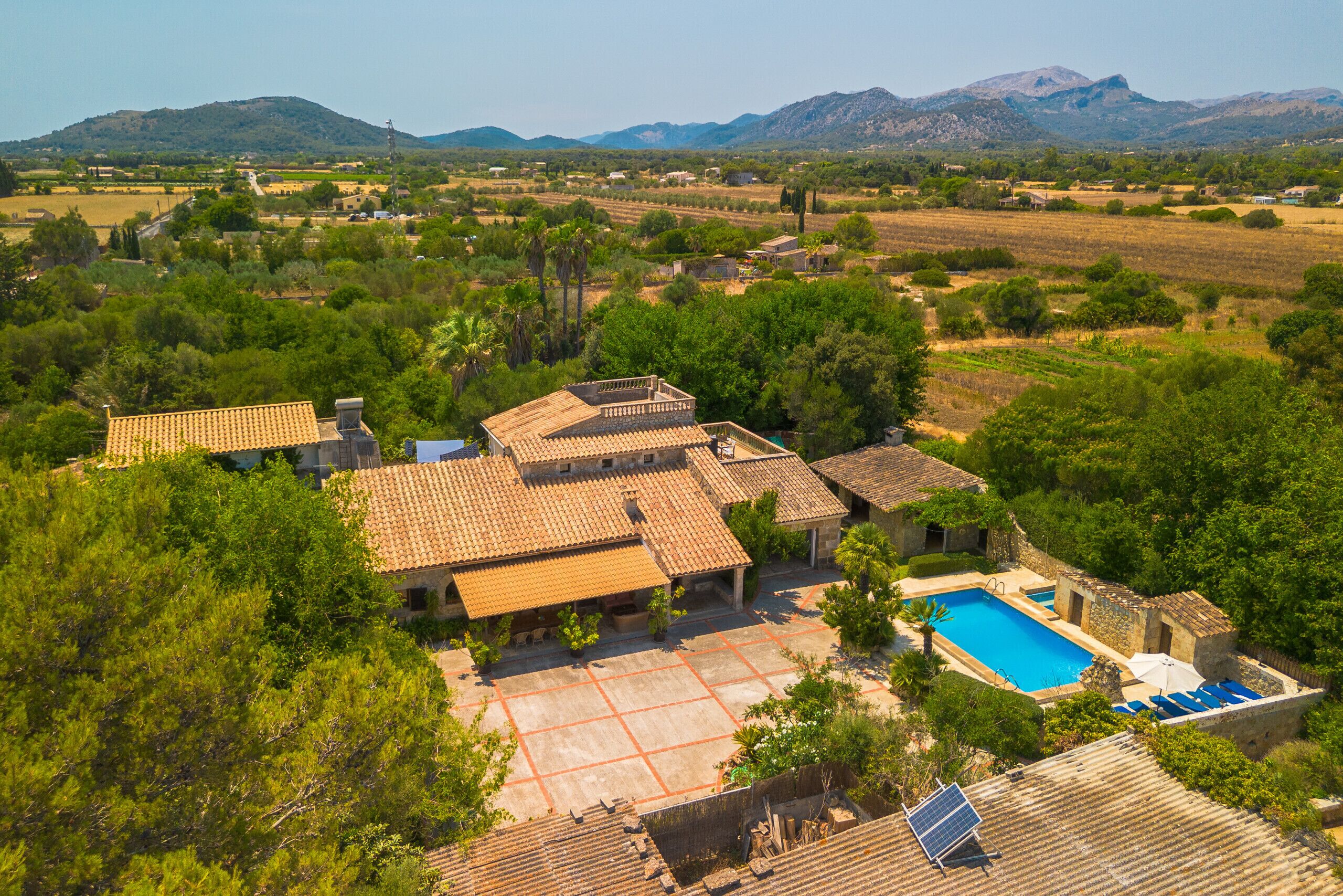 A villa with a swimming pool, surrounded by lush greenery and mountains in the background.