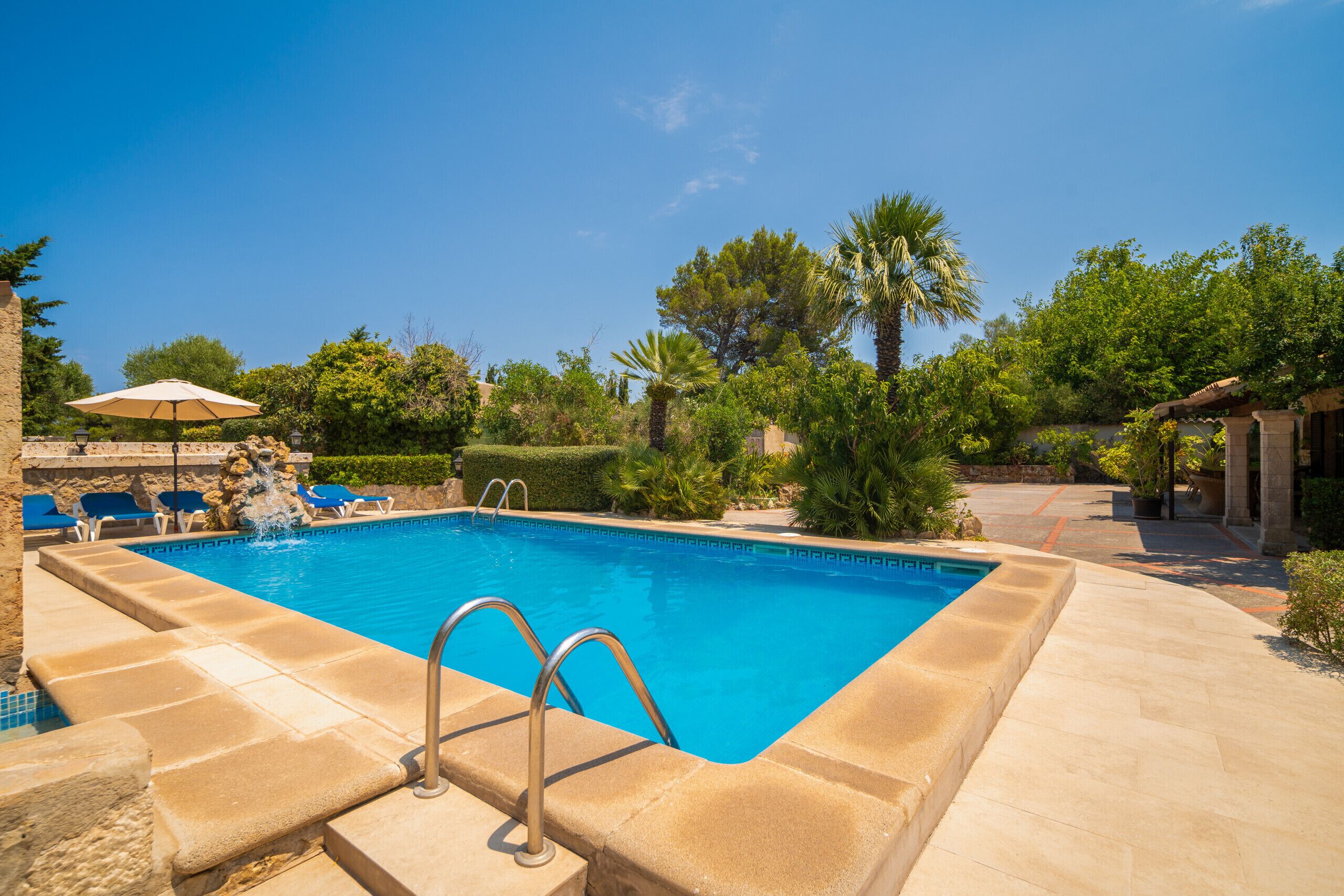 A rectangular swimming pool with a clear blue water, surrounded by a stone deck.