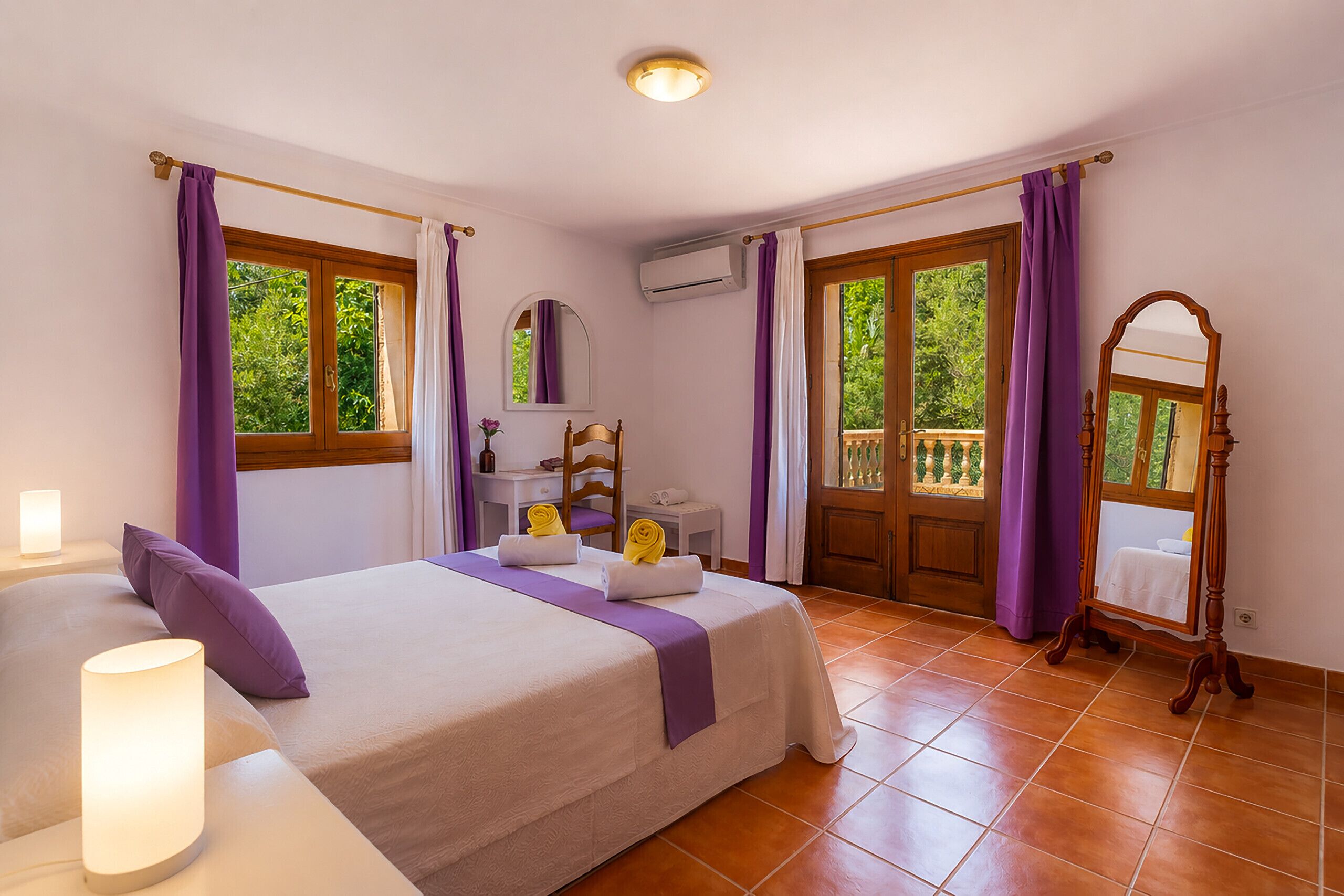 Una camera d'albergo con un letto, una scrivania, una sedia, uno specchio e una finestra con tende.