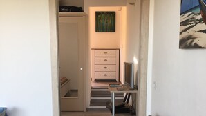 A bedroom with a bed, a desk, a chair, a wardrobe, and a painting on the wall. - Two-room apartment in Palau, 20 minutes from the Costa Smeralda in Sardinia (PALAU (OT))