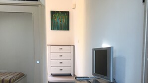 A bedroom with a bed, a desk with a computer, and a painting on the wall. - Two-room apartment in Palau, 20 minutes from the Costa Smeralda in Sardinia (PALAU (OT))