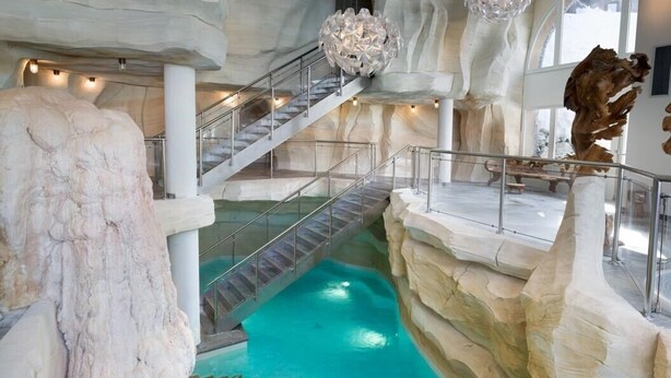 An indoor pool with a rocky landscape and a staircase.