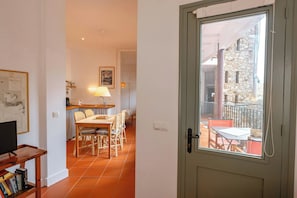 A room with a dining area, a television, and a door leading to an outdoor balcony.