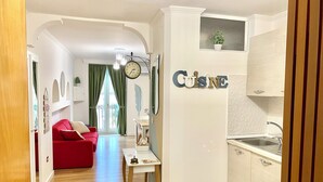 A modern apartment with a red sofa, a dining table, and a kitchen area. - SuiteCorso Vibo Valentia (Vibo Valentia)