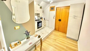 A compact kitchen with a microwave, stove, and oven. There is a wooden door and a white cabinet with drawers. - SuiteCorso Vibo Valentia (Vibo Valentia)