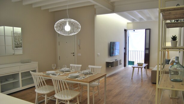 A dining area with a wooden table set for four, white chairs, and a hanging light fixture. - Cream Homes La Rambla, INTERIOR TOURISM Accommodation (Palma)