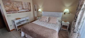Une chambre à coucher avec un lit, des lampes de chevet, une table de chevet, une commode et un tableau au mur.