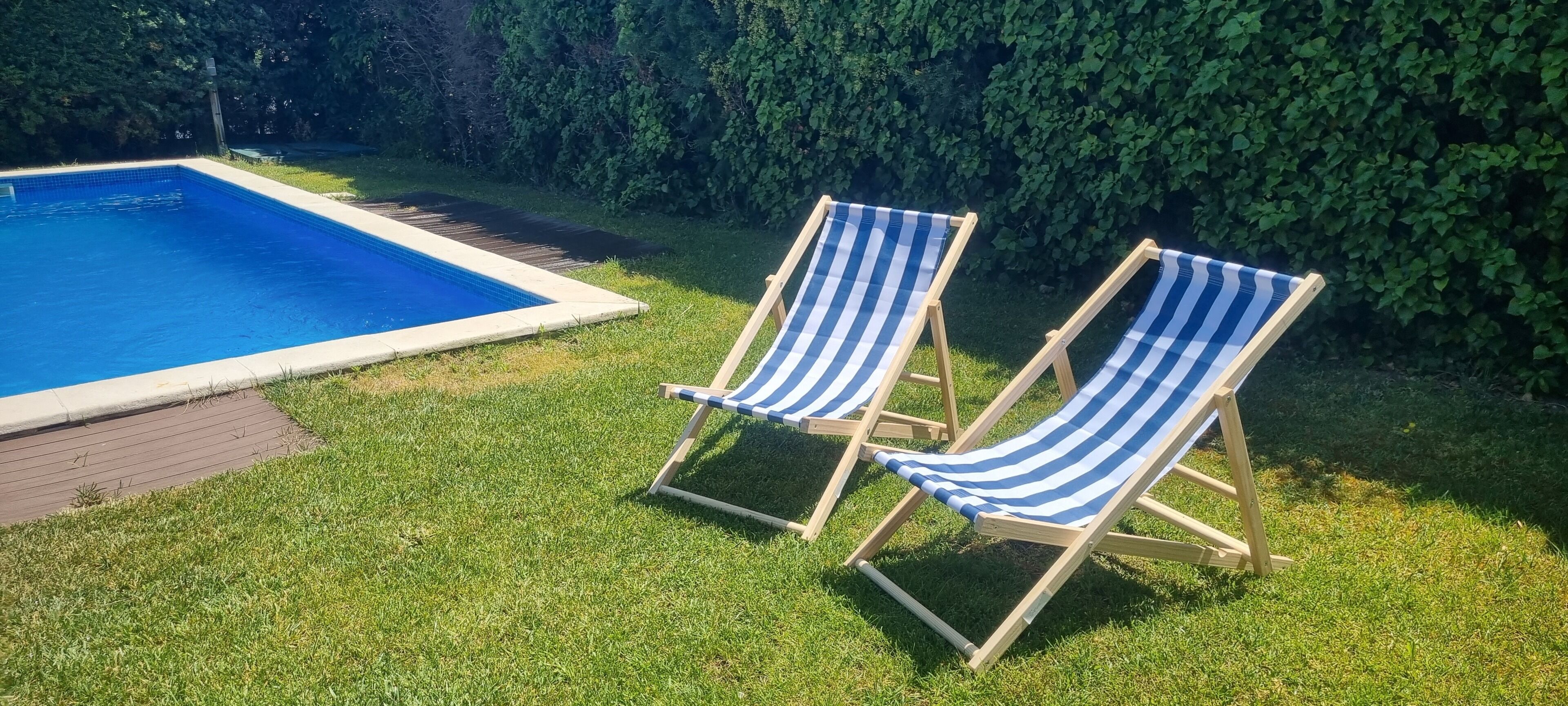 Ein Schwimmbecken mit zwei gestreiften Liegestühlen.