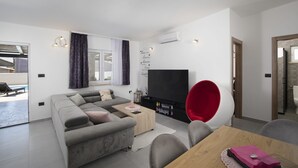 Ein modernes Wohnzimmer mit einer Couch, einem Couchtisch, einem Fernseher und einem roten Sessel.