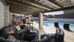 Eine Außenpatio-Terrasse mit Korbmöbeln, einem Pool und Blick auf die umliegende Landschaft.