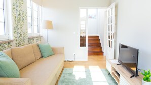 Un salon avec un canapé, un téléviseur et un escalier menant à une autre pièce.