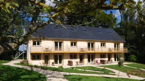 Une maison à deux étages avec un balcon, une allée en gravier et une pelouse bien entretenue.