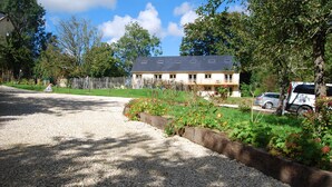 Une maison avec une allée gravillonnée, une clôture en bois et un jardin fleuri.