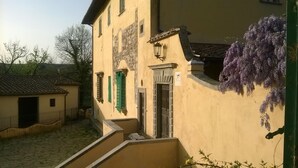 Ein Gebäude mit gelber Fassade, grünen Fensterläden und einem Balkon über der Tür.