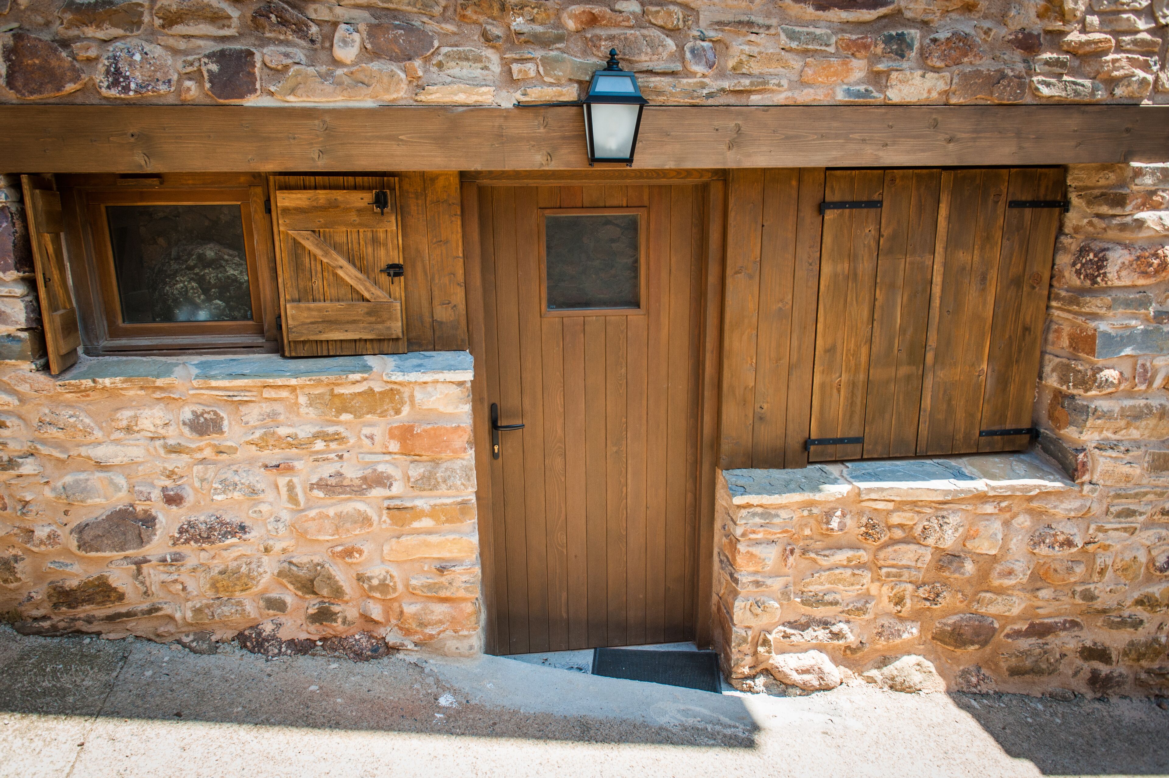 A stone building with a wooden door, a window, and a lantern above the door.