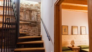 A staircase with wooden steps and a metal railing, leading to a room with a wooden ceiling and a bed with green bedding. - Old era of the 19th century Detached rural house Era del Mestre (Erinyà)
