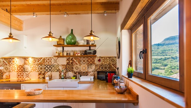 A kitchen with a wooden countertop, hanging pendant lights, a radio, and a window with a view of the countryside. - Old era of the 19th century Detached rural house Era del Mestre (Erinyà)