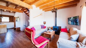 A spacious living room with wooden beams, a fireplace, and a television. - Old era of the 19th century Detached rural house Era del Mestre (Erinyà)
