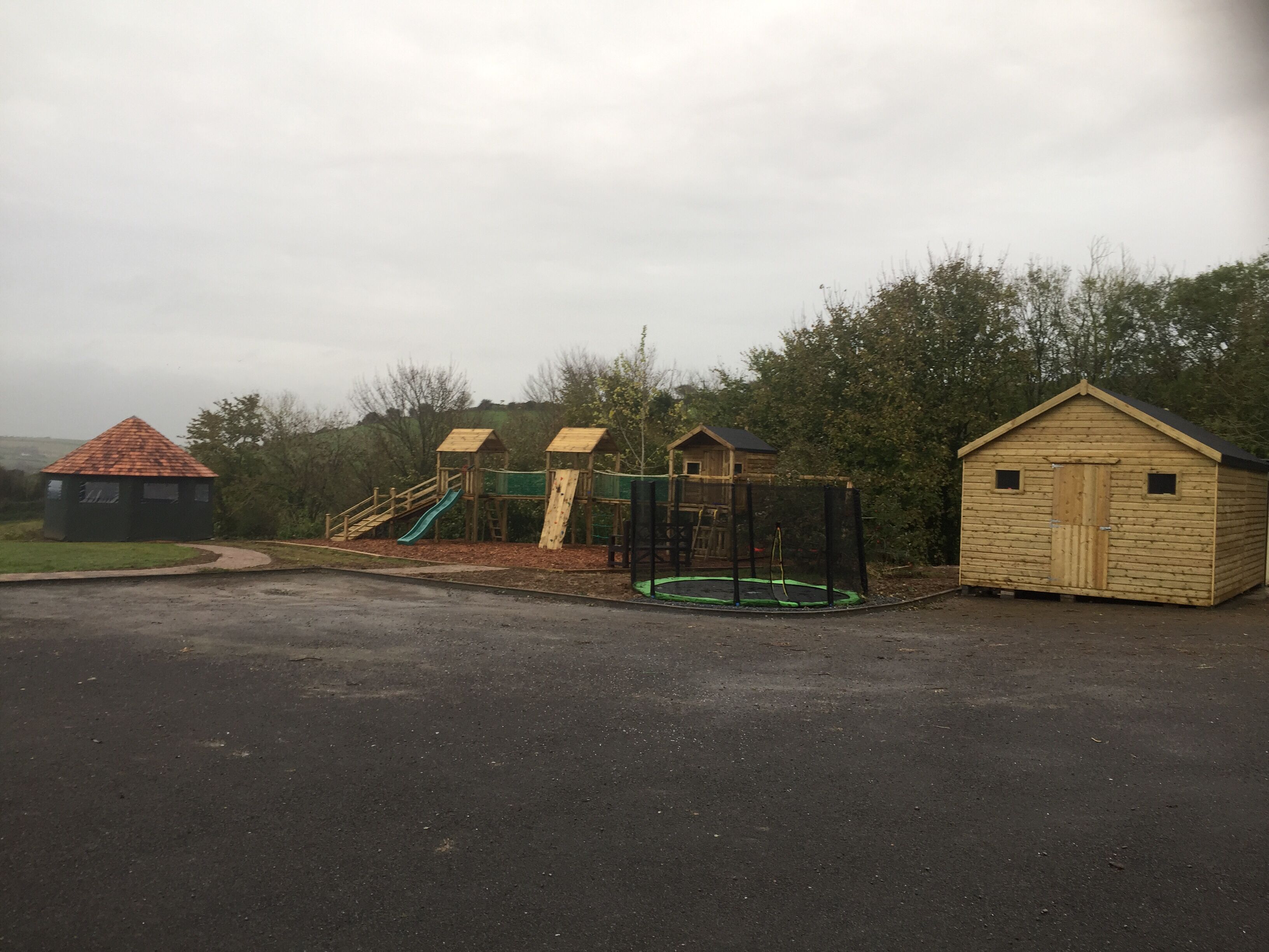 Un parque infantil con tobogán, estructuras para escalar y un trampolín.