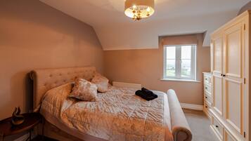 A bedroom with a large bed, a nightstand, a dresser, and a window with a view.