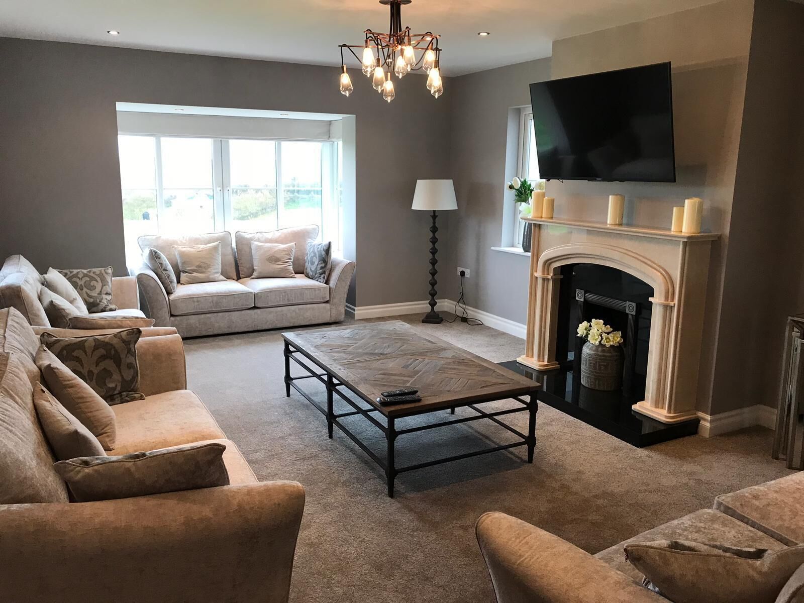 A living room with a fireplace, a sofa set, a coffee table, and a TV mounted on the wall.
