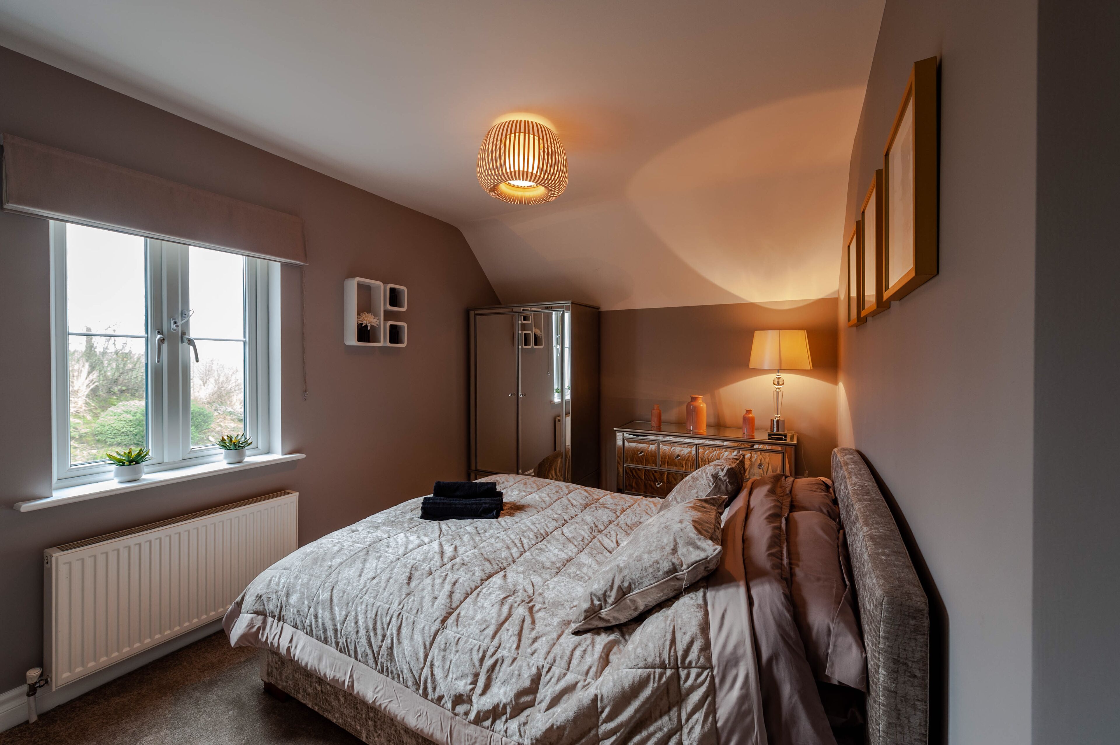 Une chambre à coucher avec un lit, un radiateur, une fenêtre, une armoire et une lampe.