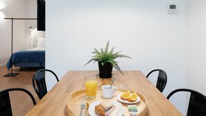 A breakfast tray with croissant, ham, cheese, orange slices, and juice on a wooden table.