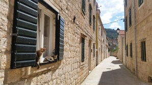 A narrow stone street with buildings on either side, featuring shutters and a clear sky. - Buena Vista Apartment Vintage View (Vis)