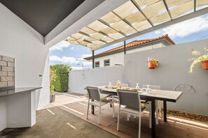 Relax in the serene patio area with a table for four, a shaded pergola, and lush greenery.