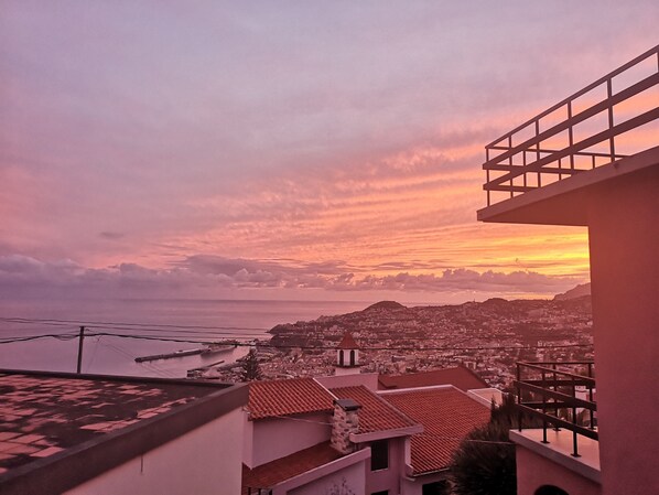 A coastal cityscape at sunset with buildings and a clear view of the sea. - Bay view apartment, Bay view apartment I (Funchal)