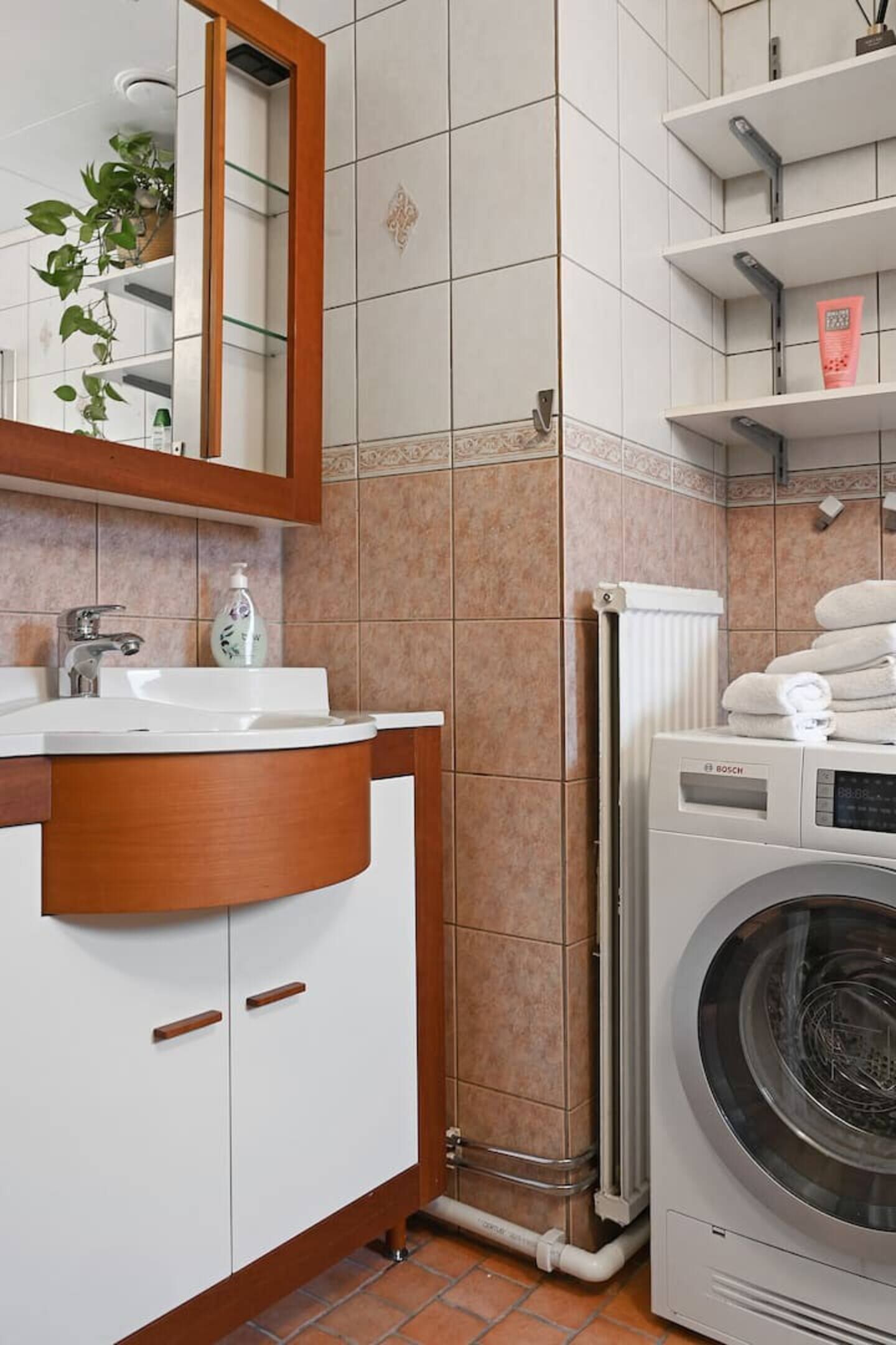 A modern bathroom with a sink, mirror, and Bosch washing machine.