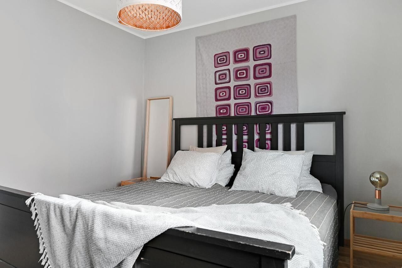 A neatly arranged bedroom with a bed, a bedside table, and a wall-mounted artwork.