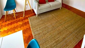 Una sala de estar moderna con un sofá, un sillón azul, una lámpara de pie y una alfombra grande.