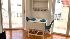 Un comedor con mesa blanca, sillas azules y suelo de madera con motivo de espiga.