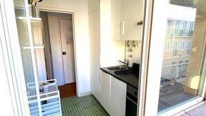Una cocina pequeña con armarios blancos, encimera negra y suelo estampado en verde.