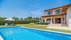 A swimming pool with lounge chairs and a house with a tiled roof. - Villa Can Salat Selva (Selva)