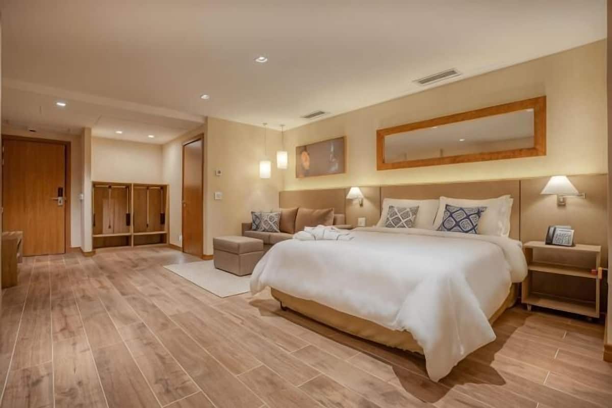 A hotel room with a large bed, bedside tables, a wardrobe, and a mirror on the wall.