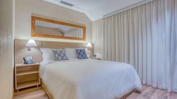 Habitación de hotel con una cama grande, dos mesitas de noche con lámparas, un teléfono y un espejo sobre la cama.