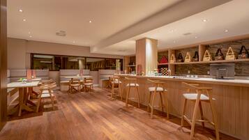 Um restaurante moderno com piso de madeira, banquetas e um balcão com diversos itens.