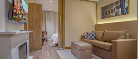 Una sala de estar moderna con chimenea, un sofá, un televisor montado en la pared y un cuadro sobre el sofá.