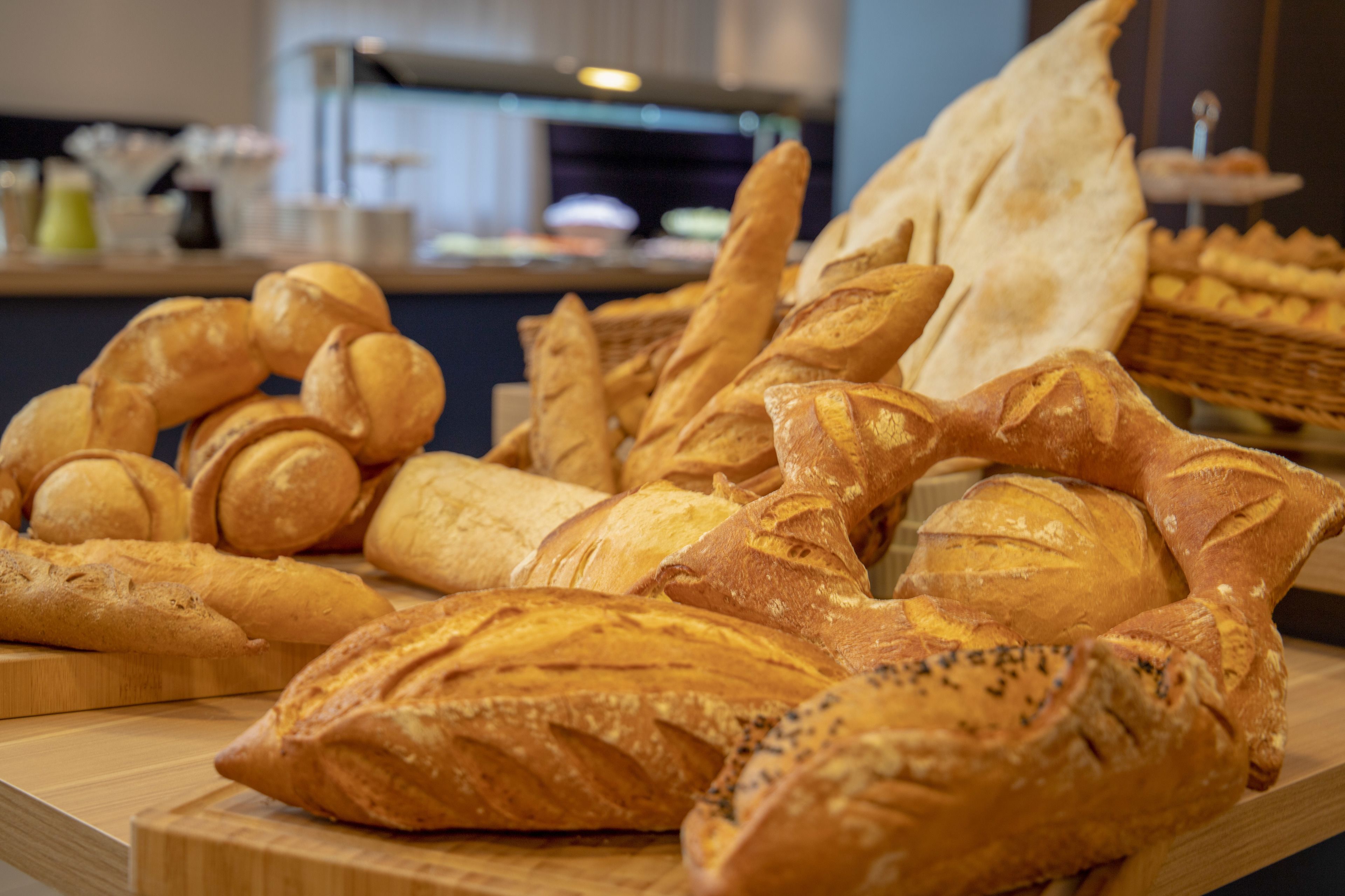 A variety of breads displayed on a wooden board in a bakery setting.