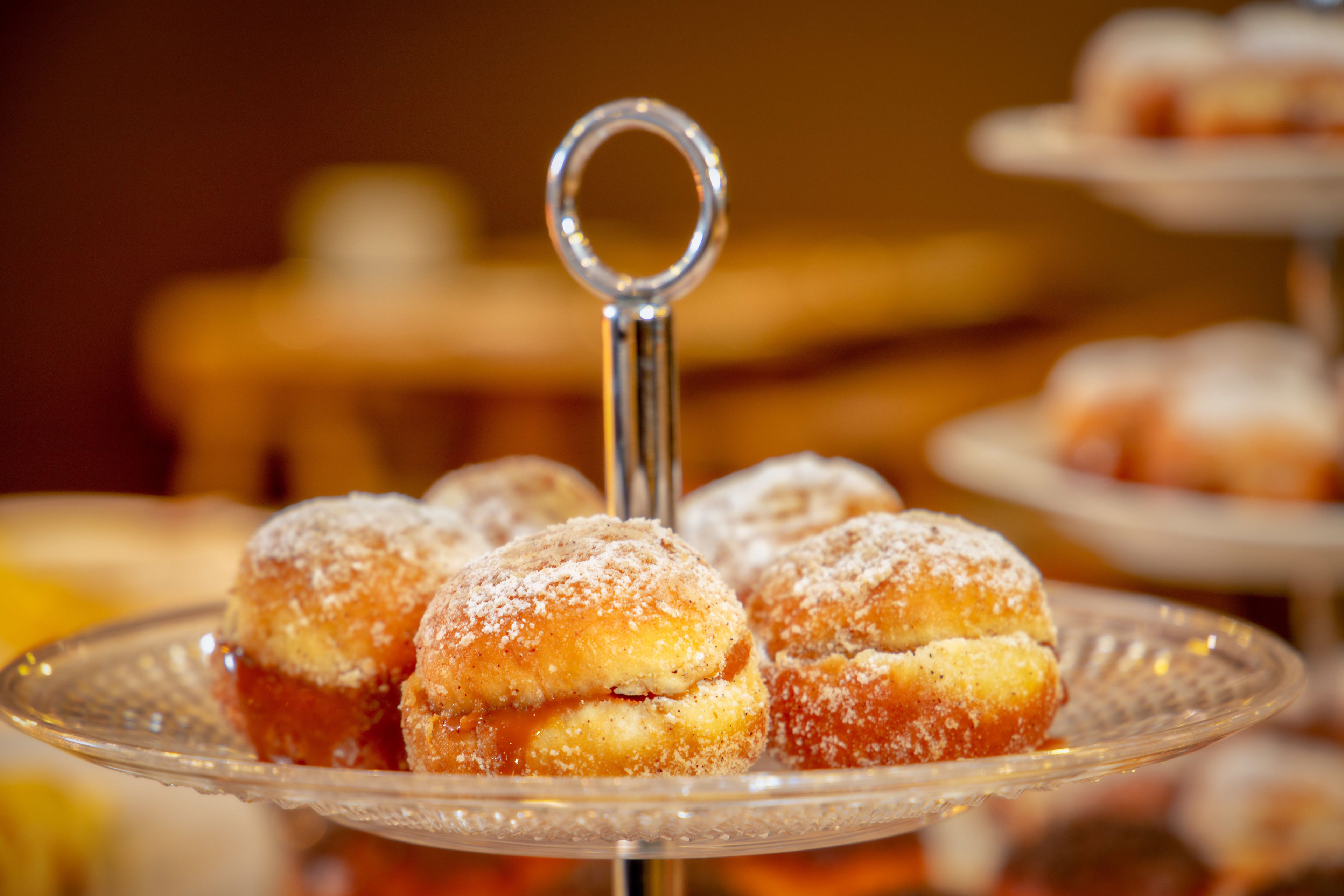 Un présentoir à desserts avec une assiette en verre sur laquelle sont disposées des pâtisseries saupoudrées de sucre glace.
