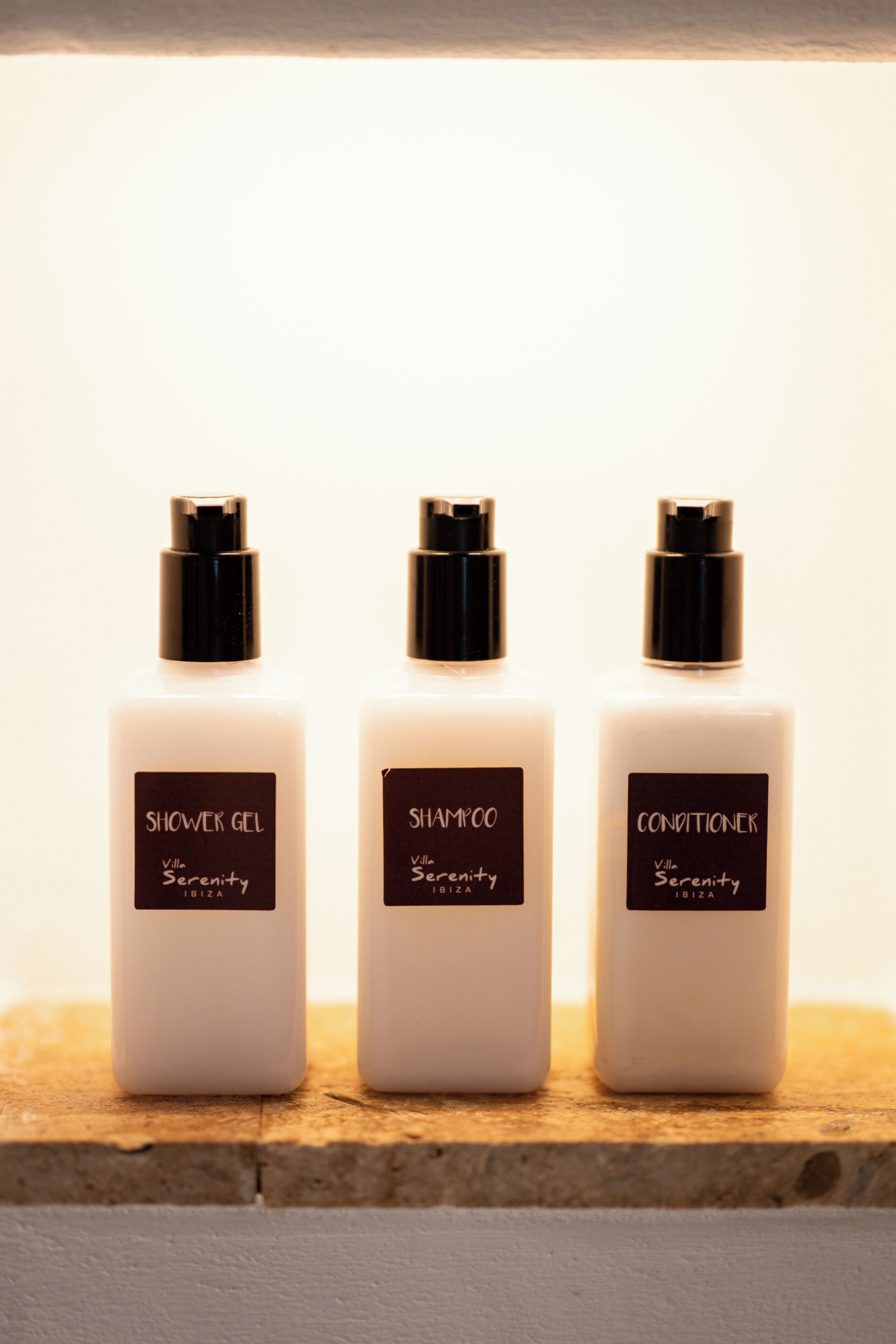 Three bottles of Villa Serenity Ibiza products on a wooden surface.